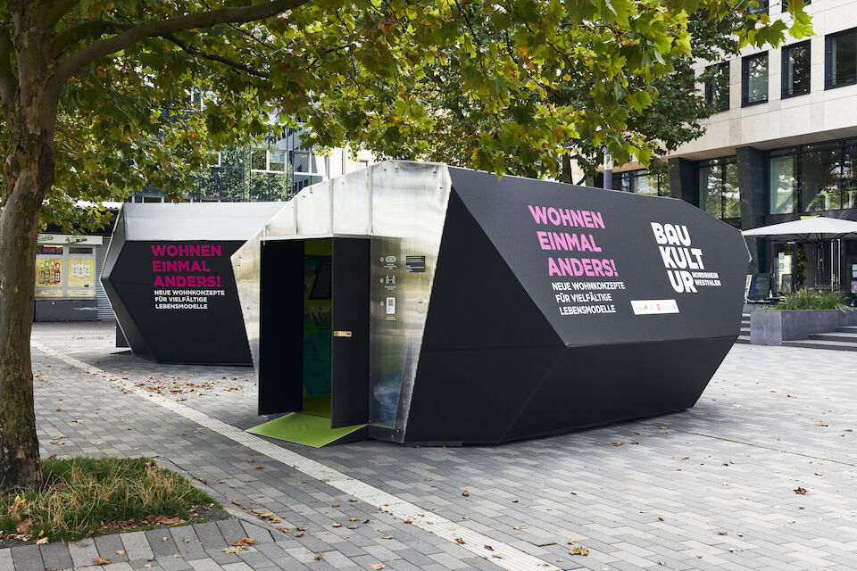 Die Ausstellung „WOHNEN EINMAL ANDERS!“ auf dem Kesselbrink in Bielefeld. Außenansicht auf die beiden temporären Pavillon-Architekturen aus Holz.