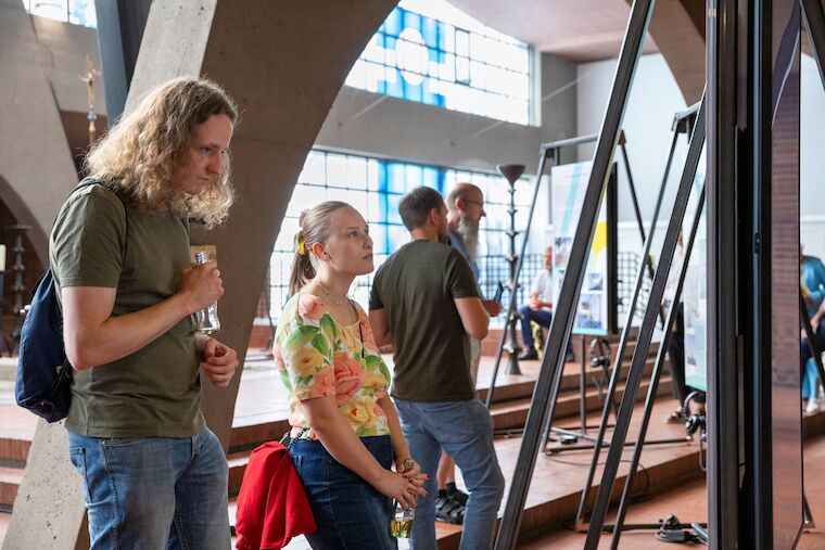 Fast andächtig liest eine junge Frau die Ausstellungstexte. Ausstellungseröffnung „Kirchen als Vierte Orte – Perspektiven des Wandels“, 1.9.2024, Heilig-Geist-Kirche, Essen. Foto: Claudia Dreyße